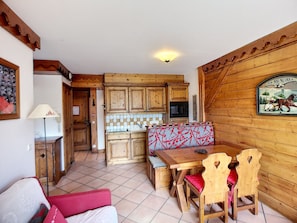 A cozy kitchen with wooden cabinets, a tiled backsplash, and a bench with red cushions.