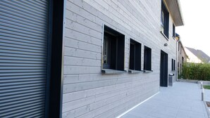A modern building with horizontal siding, a covered walkway, and a small window. - La Griffe à Foin, Kaysersberg - 300 m² House - Private Jacuzzi Sauna  (Kaysersberg)