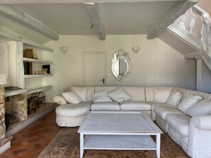 A spacious living room with a white sectional sofa, a coffee table, and a stone fireplace.