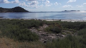 A coastal landscape with a beach, grassy foreground, and distant hills under a clear sky. -  Studio for 2 people in Bages in the heart of the Narbonnaise Regional Natural Park (Bages)