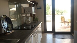 A modern kitchen with a stove, sink, and a large window. -  Studio for 2 people in Bages in the heart of the Narbonnaise Regional Natural Park (Bages)