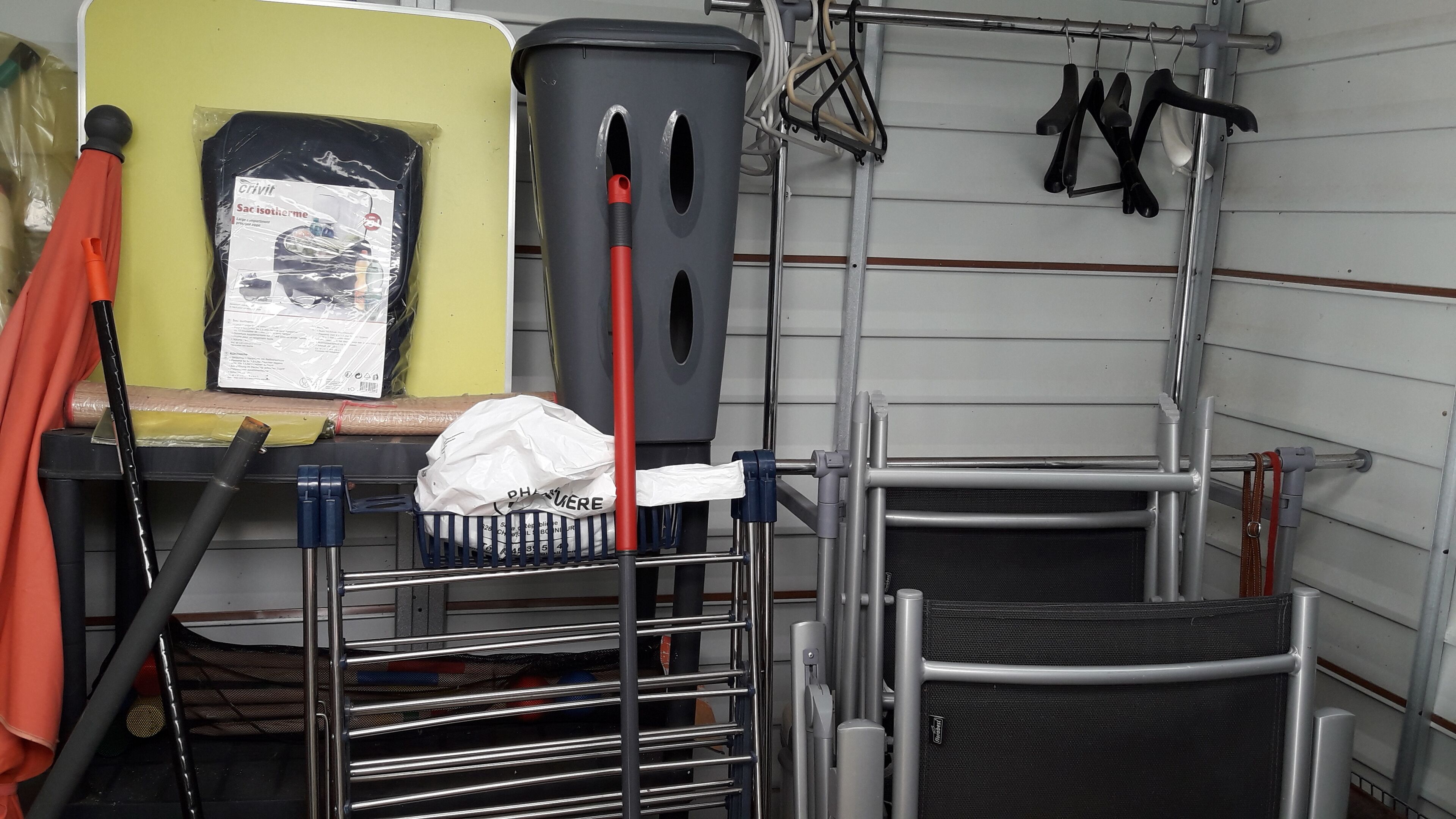 Un espace de rangement équipé d’étagères, d’une poubelle et d’un présentoir contenant divers objets.