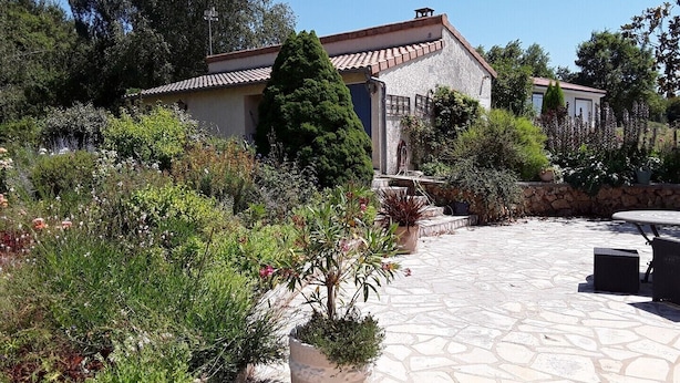 A stone-paved patio with a stone wall and a garden with various plants and a fountain. - Meublé de tourisme ** "chezphoenixette (Nieuil)
