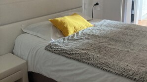 Une chambre à coucher avec un lit, une table de chevet et une porte donnant sur une autre pièce.