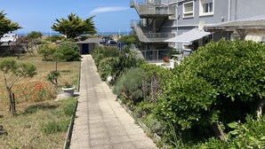 Un chemin menant à un immeuble d’habitation doté d’un balcon et offrant une vue sur la mer.