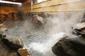 A hot spring area with stone walls and a bamboo backdrop. - Madarao Kogen Hotel (Myoko)