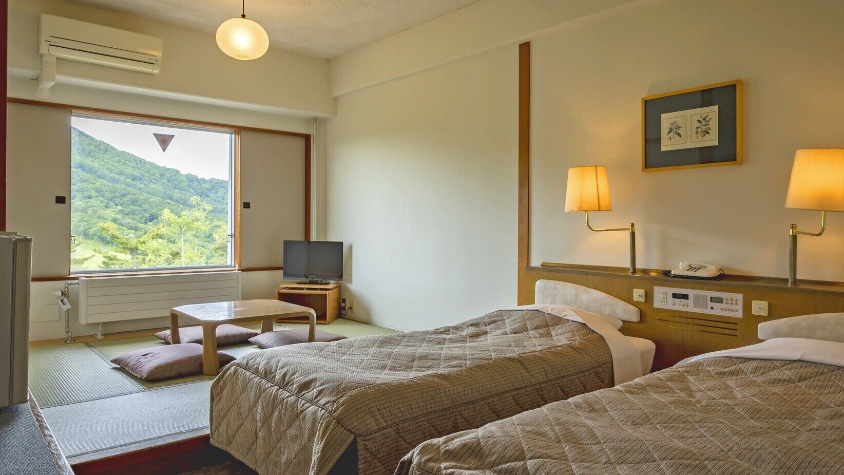 A hotel room with two beds, a TV, a desk, and a view of a green landscape.
