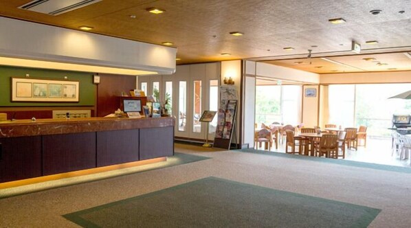A reception area with a counter, seating area, and large windows. - Madarao Kogen Hotel (Myoko)