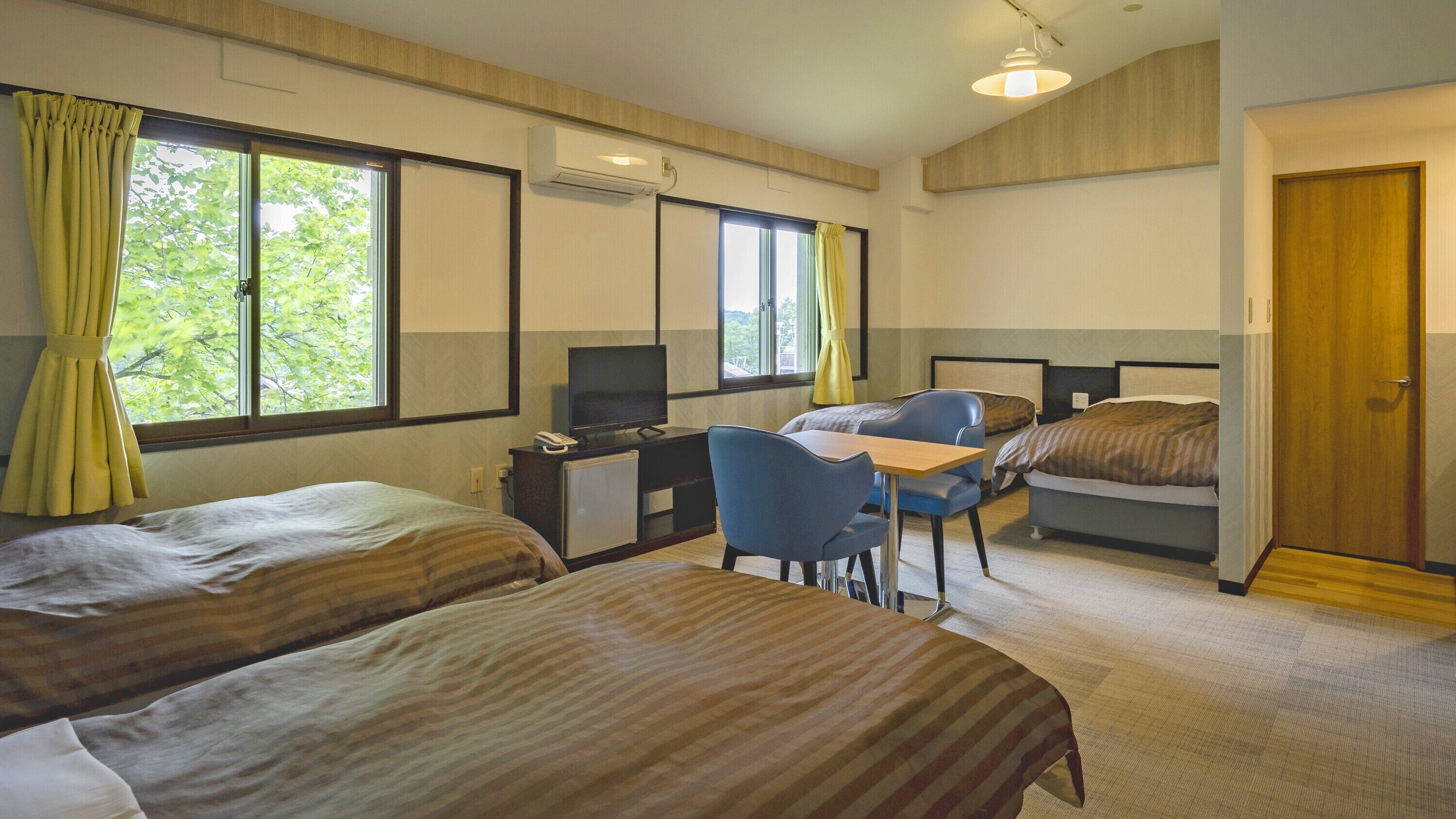 A hotel room with two beds, a desk with a computer, a chair, and a TV.