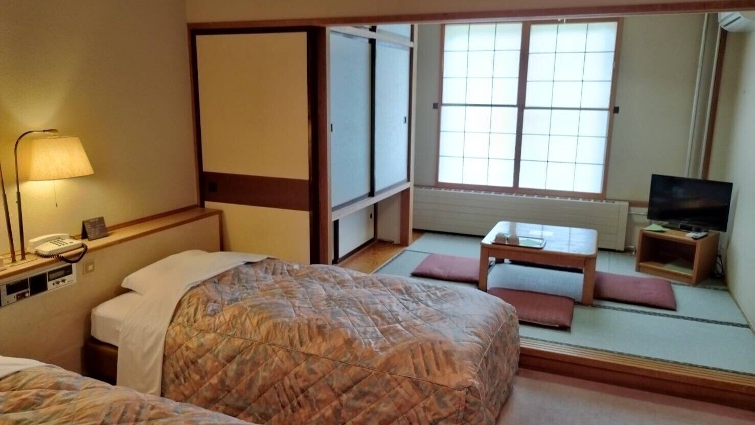 Ein Hotelzimmer mit einem Bett, einem Schreibtisch, einem Fernseher und einer Schiebetür.