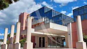 A modern building with a glass facade, a central entrance with steps, and a red and beige color scheme.