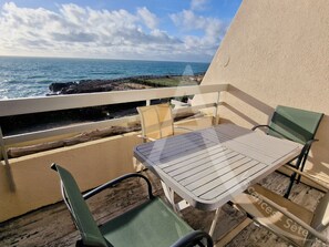 Een balkon met een tafel en stoelen, met uitzicht op de oceaan.