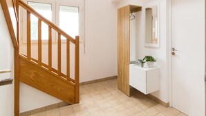 Un escalier menant à un palier, une salle de bain blanche avec un meuble en bois et un miroir, et un sol carrelé.
