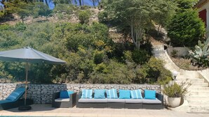 Zona de piscina con sillones de descanso y un muro de piedra.