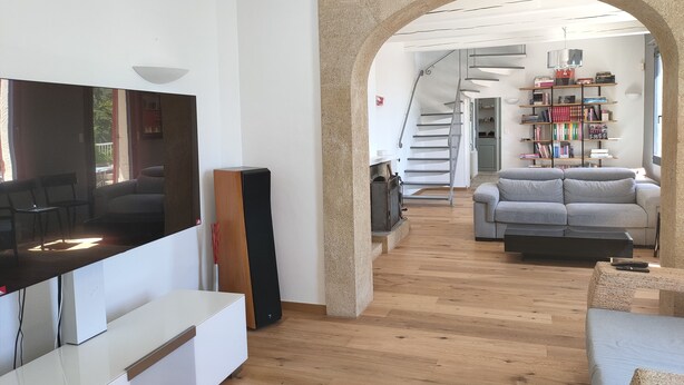 Una sala de estar moderna con un televisor de pantalla plana, un mueble blanco para entretenimiento, un sofá gris y una estantería.