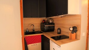 A compact kitchen with a sink, a toaster, a kettle, and a coffee maker.