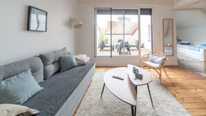 Un salon moderne avec un canapé gris, une table basse ronde et un fauteuil en osier.
