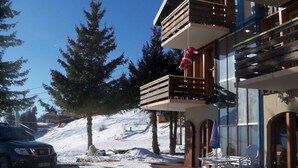 Ein modernes Gebäude mit einem Holzbalkon, einer Seilbahn im Hintergrund und einer verschneiten Landschaft.