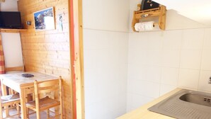 A kitchen with a wooden table, chairs, a stove, and a sink. - Cozy apartment for 4 in Arêches-Beaufort, close to ski lifts, shops, and pool (Arêches-Beaufort)