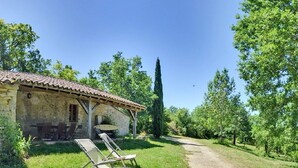 A rustic stone building with a tiled roof, a small porch, and two lounge chairs outside. - Charming cottage for 12 people - Wilderness + private pool (Thézac)