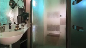 Ein Badezimmer mit Duschkabine, Waschbecken und Pflegeprodukten sowie einem Spiegel.