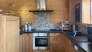 A modern kitchen with wooden cabinets, a stainless steel oven, and a patterned backsplash.