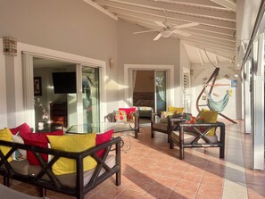 A spacious patio with outdoor furniture, a ceiling fan, and a hammock.