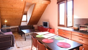 Un loft acogedor con comedor, sofá, televisor y cocina equipada con microondas.