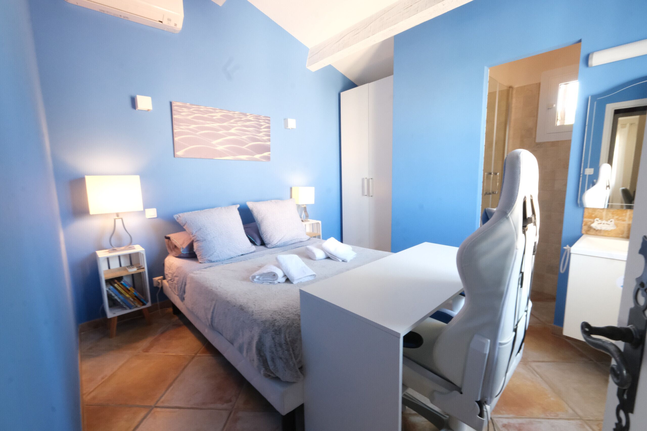 A bedroom with a bed, bedside tables, a desk, and a chair.