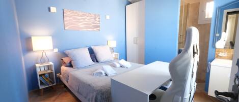 A bedroom with a bed, bedside tables, a desk, and a chair.