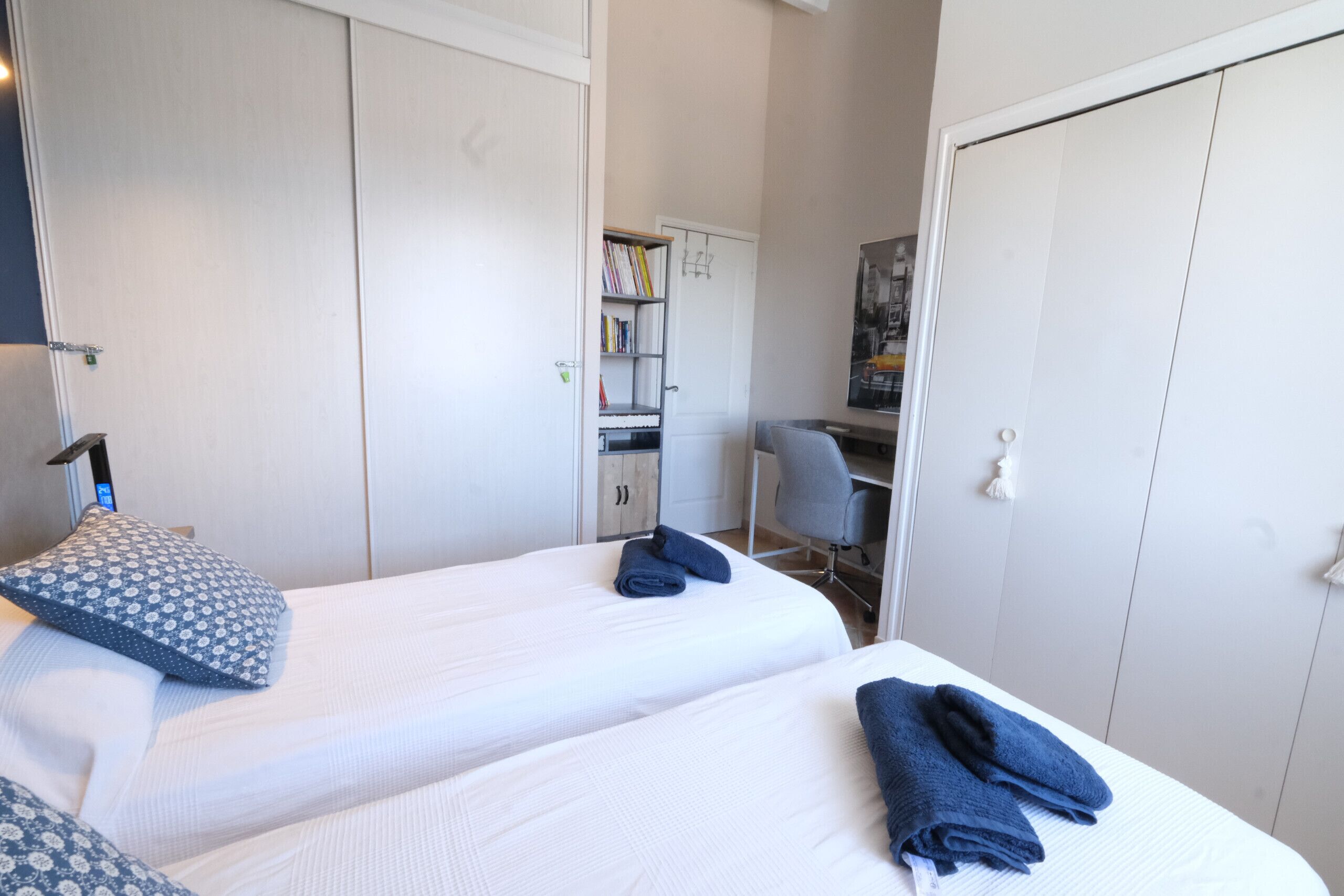 A hotel room with two beds, a desk, and a wardrobe.