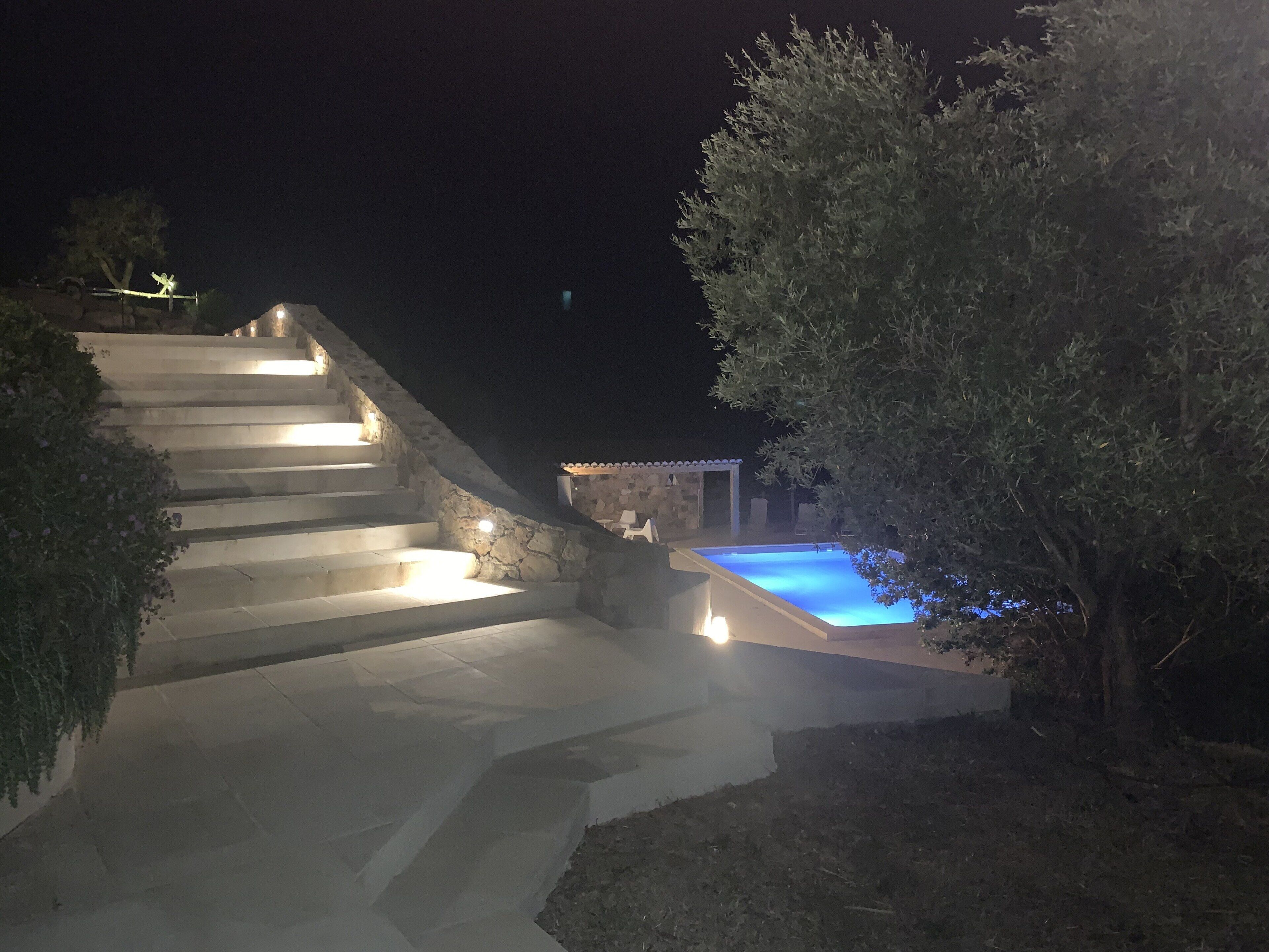 A stone staircase leading to a pool area at night.