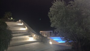 A stone staircase leading to a pool area at night.