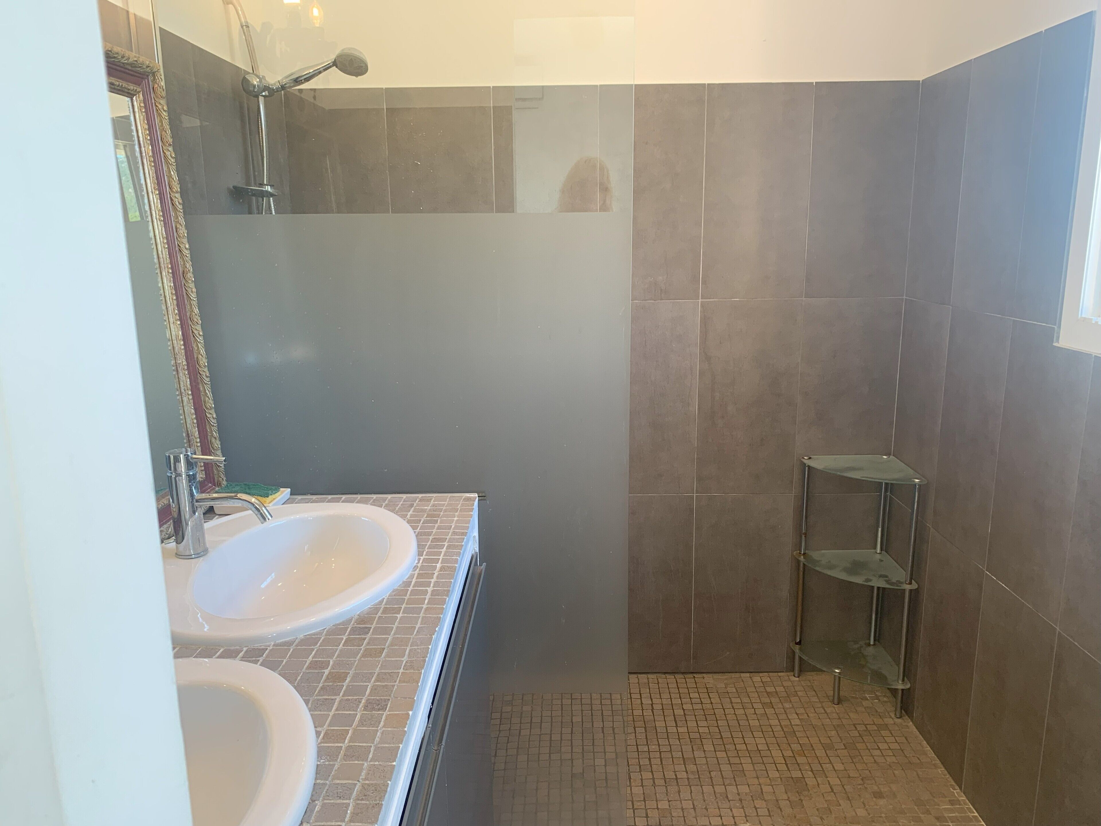 Une salle de bain avec deux lavabos, une douche et une étagère en verre.