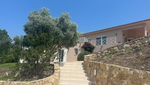 A stone staircase leading to a house with a beige facade and white railings.