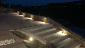 A nighttime outdoor staircase with stone railings and steps, illuminated by small lights.