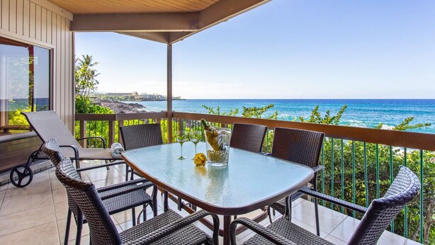 Un espace extérieur abrité, aménagé pour les repas, avec une table et des chaises, offrant une vue sur la côte.
