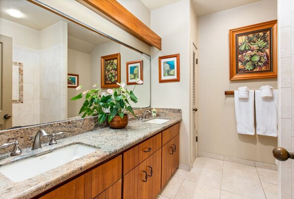 A bathroom with two sinks, a large mirror, wooden cabinets, and a potted plant.