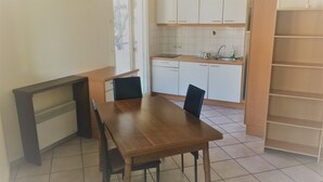 Une cuisine avec des meubles blancs, une table à manger en bois et des chaises.