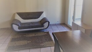 Une pièce avec un canapé gris et blanc, un tapis à motifs et une table en bois.