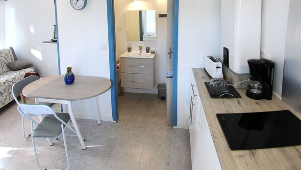 A compact kitchen with a dining area, a small table, and a chair.