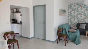A room with a kitchenette, a dining area with chairs, a sofa, and a patterned wall.