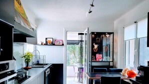 Une cuisine moderne avec un coin repas, dotée d’un sol carrelé en noir et blanc, d’un four encastré et d’une table à manger avec des chaises.