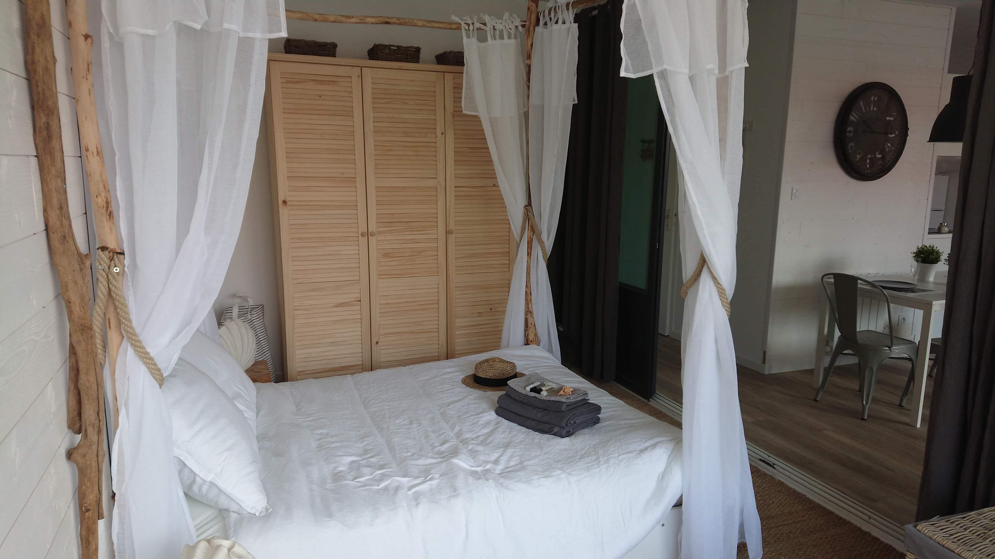 Un dormitorio con cama con dosel, armario de madera y vistas al exterior.