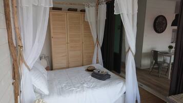 Un dormitorio con cama con dosel, armario de madera y vistas al exterior.
