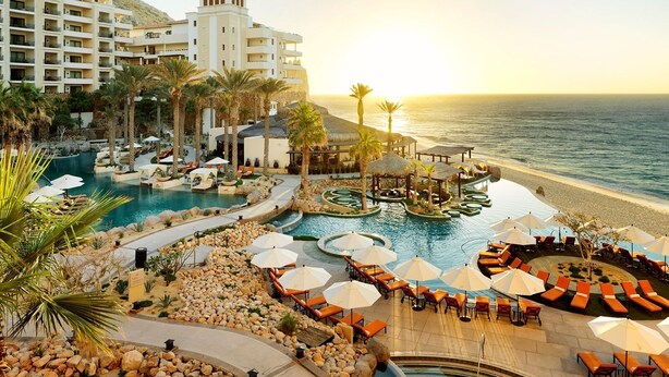 Un resort con varias piscinas, tumbonas y vistas a la playa.
