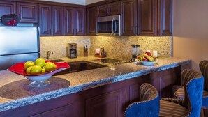 Una cocina con alacenas de madera oscura, un refrigerador de acero inoxidable, un microondas y una encimera de granito.