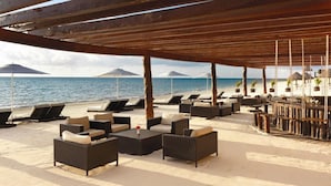 A beachside lounge with wicker furniture, umbrellas, and a view of the sea. - Luxury Suite in Moon Palace  Cancún (Cancún)