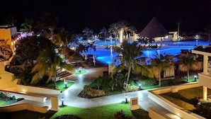 A resort with a large swimming pool, palm trees, and well-lit pathways. - Luxury Suite in Moon Palace  Cancún (Cancún)