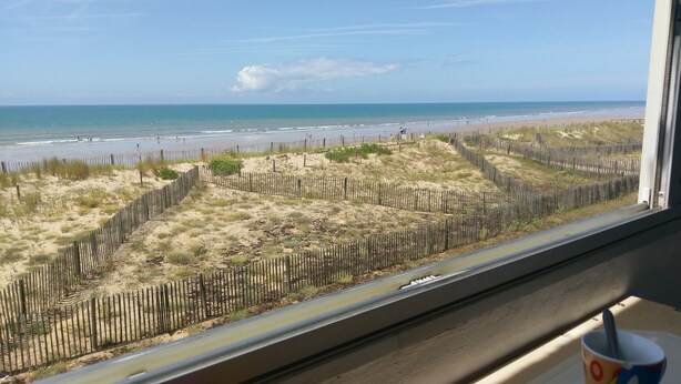 A beach view with a wooden fence and a clear sky.